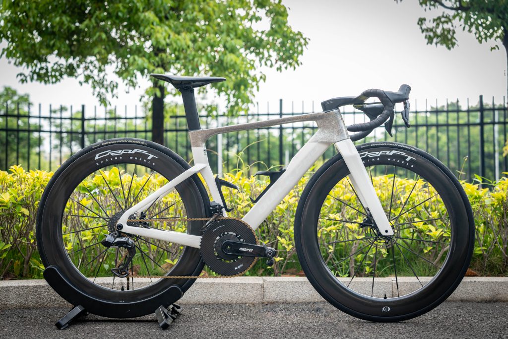 An ER:ONE road bike parked infront of some flowers.